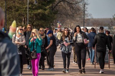 BELGRAD, SERBIA - 27 Mart 2021: Belgrad 'ın Sırp bir caddesinde kalabalığın ortasında patlamış mısır yiyen iki kadın, arkadaş ve Sırp hakkında seçici bulanıklık. Patlamış mısır ikonik bir sokak yemeğidir..