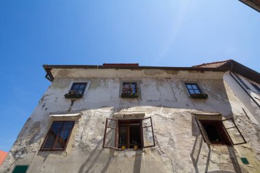 Eski bir apartman binasının tipik Orta Çağ cephesi, harap olmuş, eski bir kasabanın sokağında yenilenmeye ihtiyacı var, Slovenya 'nın Ljubljana şehrinin tarihi merkezi, pencereleri açık..