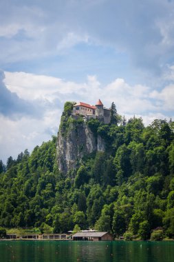 Bled Gölü 'nün Panorama' sı Blejsko Jezero, şatosu Blejski Hrad ile birlikte Julian Alpleri 'nin dağlarıyla dolu bulutlu bir yaz boyunca. Bled Castle Slovenya 'nın büyük bir anıtı