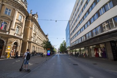 LJUBLJANA, SLOVENIA - JUNE 14,2021: Slovenska cesta street, deserted, with a man passing by on an electric scooter. it is the main street of the city center of the Slovenian capital city.