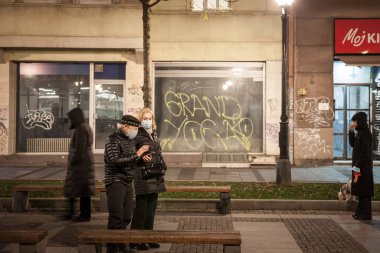 BELGRAD, Kasım 18, 2021: Yaşlı yaşlı erkek ve kadın, çift, yüz maskesi takıyor, Coronavirüs 19 sağlık krizi sırasında geceleri Belgrad sokaklarında uyanıyorlar.