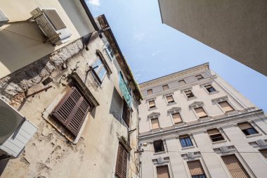 Typical mediterranean old narrow street with southern european architecture, with ancient buildings with balconies, in the old town of Rijeka, one of the main streets of Istria, on Adriatic sea