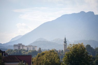 Panorama of the suburbs of Villach with a selective blur on the steeple clocktower of Pfarrhoff Sankt Martin Kirche, or the Parish Church of Saint Martin, a catholic church of Villach, Austria, Carinthia.