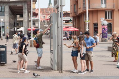 ZAGREB, CROATIA - 20 Haziran 2021: Bir haritaya bakan, kendilerini yönlendirmeye çalışan bir grup genç turist, Hırvatistan 'ın Zagreb şehir merkezinde yaz seyahati sırasında kayboldular.