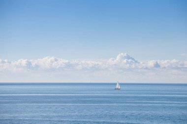 Adriyatik denizinin panoraması, güneşli mavi gökyüzü, bir yelkenli, ufuktan geçen bir yelkenli, tatillerde ve yaz tatillerinde.