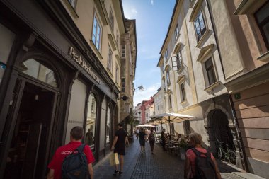 LJUBLJANA, SLOVENIA - 14 Haziran 2021: Stari Trg caddesindeki eski Austrohungarian ortaçağ binaları yazın Ljubljana şehir merkezindeki dükkanların ve butiklerin önünden geçen insanlar.