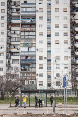 BELGRAD, SERBIA - 5 Şubat 2022: Novi Beograd 'daki 61. Blok' un yüksek binalarının önündeki otobüs durağında bekleyen insanlar, geleneksel bir komünist grup.