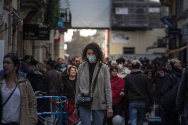 BORDEAUX, FRANCE - 19 Şubat 2022: Coronavirus Covid 19 krizinde Bordeaux 'da maskeli koruyucu teçhizat takmış bir kalabalığın içinde yürüyen bir kadın, genç kız, seçici bulanıklık