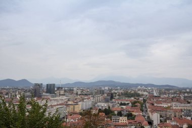 Slovenya 'nın başkenti Ljubljana' nın panoramik manzarası yukarıdan çekilmiş bulutlu gri gökyüzü öğleden sonrasında arka planda yerleşim kuleleri ile görülmüş. Ljubljana Slovenya 'nın en büyük şehri ve başkentidir.