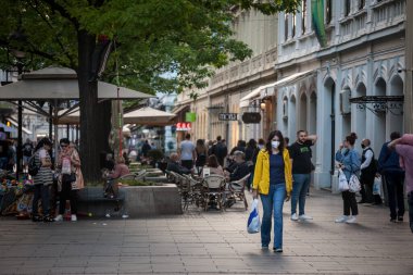 BELGRAD, SERBIA - 24 Mayıs 2021: Coronavirus Covid 19 krizinde gıda torbaları da dahil olmak üzere markette yürüyen, yüz maskesi koruyucu ekipman takan genç kız