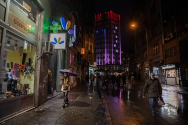 BELGRAD, SERBIA - NOVEMBER 11, 2021: Coronavirus covid 19 sağlık krizi sırasında, yağmurlu havada akıllı telefonuyla telefon görüşmesi yapan yüzü maskeli genç bir kadın hakkında seçici bulanıklık