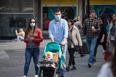BELGRAD, SERBIA - 27 Mart 2021: Avrupalı bir aile, bir anne ve bir bebek arabasında, Coronavirus Covid 19 krizinde yüz maskesi koruyucu ekipman takarak yürüyen bebeklerinde seçici bulanıklık
