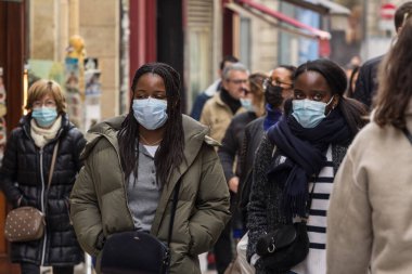 BORDEAUX, FRANCE - 19 Şubat 2022: Coronavirus covid 19 krizinde Bordeaux 'nun kalabalık sokaklarında solunum maskesi takarak yürüyen iki siyah kız, genç kız, arkadaş seçici bulanıklık