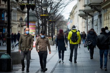 BELGRAD, SERBIA - 6 Mart 2021: Kışın Belgrad sokaklarında Coronavirus covid 19 krizinde solunum maskesi takmış iki erkek ve arkadaş seçici bulanıklık