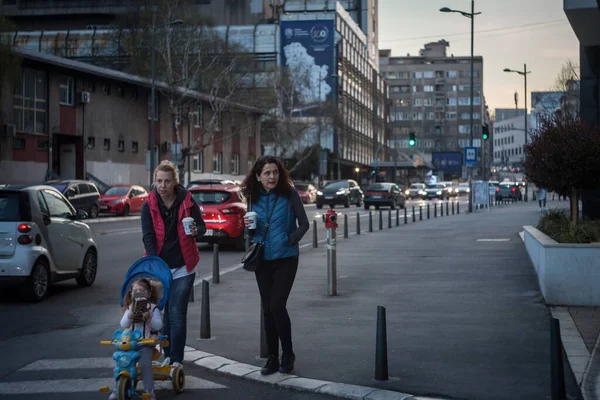 BELGRAD, SERBIA - 1 Nisan 2021: İki kadın, anne, bir çocuğu gezdiren, gülümseyen, kahve bardaklarını tutan, sıcak bir içecek içen seçici bulanıklık.
