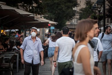 BELGRADE, SERBIA - JULY 12, 2021: Old senior man wearing a respiratory face mask walking in the Kneza Mihailova street of Belgrade, during the coronavirus covid 19 health crisis