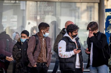 BORDEAUX, FRANCE - 25 Şubat 2022: Coronavirus covid 19 krizinde solunum maskesi takan, Bordeaux, Fransa 'da otobüs bekleyen beyaz ve siyah, beyaz erkekler için seçici bulanıklık