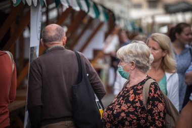 LJUBLJANA, SLOVENIA - SEPTEMBER 18, 2021: Kalabalığın ortasında yaşlı bir kadın, maske takıyor, Coronavirus covid 19 krizi sırasında Ljubljana caddesinde uyanıyor
