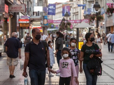 BELGRAD, SERBIA - 11 AĞUSTOS 2021: Hintli turistler, bir aile, bir anne, bir baba, bir kız çocuğu, Coronavirus Covid 19 krizinde yüz maskesi takmış, gezen ve gezen bir kalabalık tarafından çevrelenmiş.