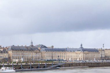 BORDEAUX, FRANCE - FEBRUARY 20, 2022: Panorama of the garonne quay (quais de la garonne), in Bordeaux, with the place de la bourse square during a winter afternoon clipart