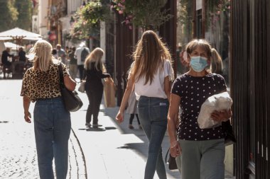 LJUBLJANA, SLOVENIA - SEPTEMBER 15, 2021: Yaşlı yaşlı kadın, tek başına, maske takmış, Coronavirus covid 19 krizi sırasında Ljubljana caddesinde uyanan