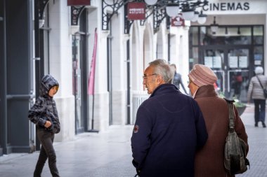 ARCACHON, FRANCE - 22 Şubat 2022: Yaşlı bir çiftte seçici bulanıklık, yaşlı bir erkek ve kadın, evli, yürüyen, genç bir çocuğu izleyen, arka planda bulanık,.