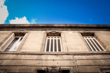 Fransa 'nın Bordeaux kentindeki tipik eski bir Fransız yerleşim yerinin dış cephesi, serbest taştan yapılmış, apartman daireleri, güneybatı Fransız mimarisi ve bazı metal at gözlükleri ile ev sahipliği yapıyor.