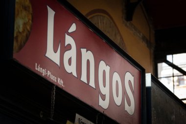 BUDAPEST, HUNGARY - FEBRUARY 26, 2022: Selective blur on a sign on a stall of Nagyvasarcsarnok Budapest market indicating langos is sold. Langos is a hungarian deep fried street food