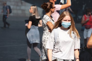 LJUBLJANA, SLOVENIA - SEPTEMBER 15, 2021: Selective blur on young woman, alone, wearing a facemask, waking in street of Ljubljana during coronavirus covid 19  crisis