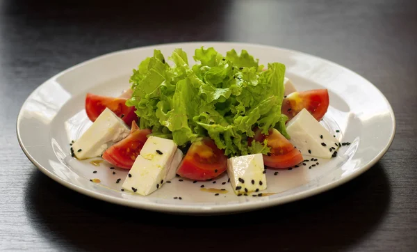 Листья салата с помидорами и сыром на тарелке — стоковое фото