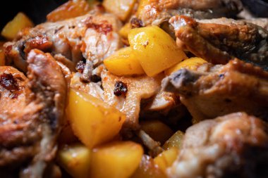 Kızarmış tavuk kanatları ve patatesler bir tavada pişirilir, yakın plan ve sığ alan derinliği vardır.