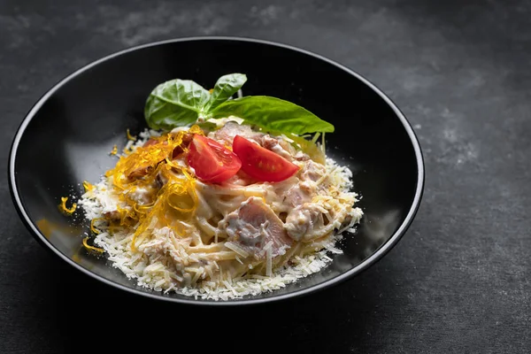 Siyah tabakta peynirli makarna ve fesleğen.