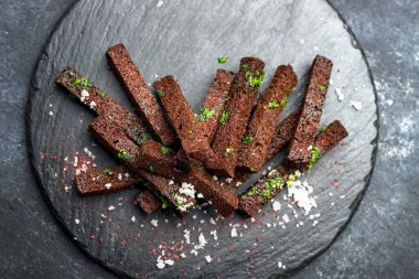 Siyah arka planda sarımsak tuzu ve otlu siyah ekmek birası.