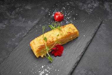 Veliaht patates graten ve siyah bir taş üzerinde vişneli domates.