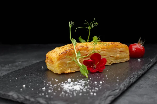 Rallado de papas Dauphinua con tomates cherry sobre una piedra negra —  Fotos de Stock