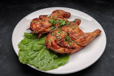 Koyu bir arka planda, tabakta marul yaprağıyla ızgara tavuk.