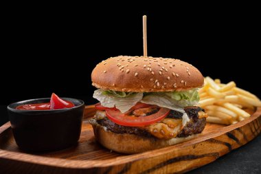Etli domates ve peynirli hamburger, patates kızartması ve sos.