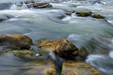 Dağ nehri, fotoğrafın dibinden uzun süre taşlarla çevrili.