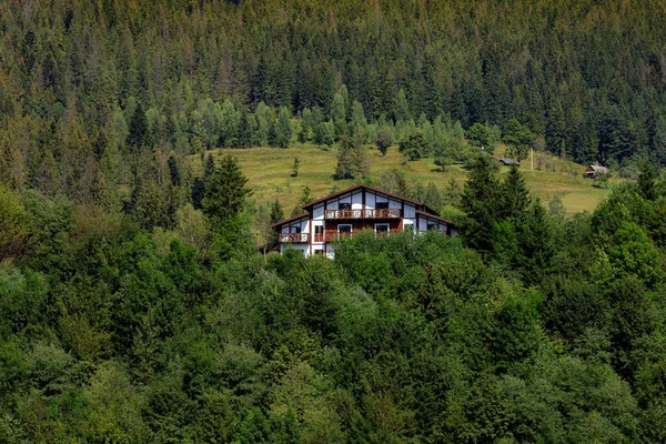 Casas de madera en las montañas entre el bosque, en una pendiente, nubes y cielo azul — Foto de Stock