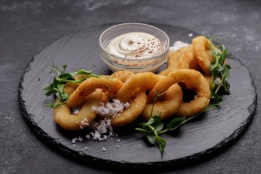 Kızarmış soğan halkaları ve üzerine sos.