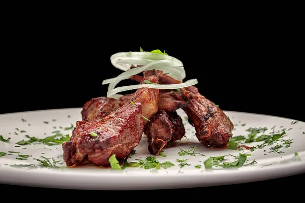 Costillas de cerdo a la parrilla con cebollas y hierbas, sobre un fondo oscuro — Foto de Stock