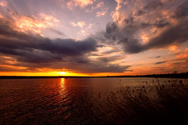 Belo pôr do sol no lago com nuvens e raios de sol — Fotografia de Stock