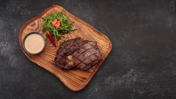 Gegrilltes Steak mit Sauce und Kräutern, auf einem Holzbrett — Stockfoto