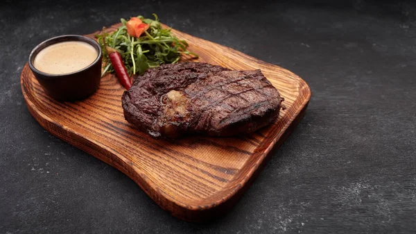 Grillezett steak szósszal és fűszerekkel, fapadlón — Stock Fotó