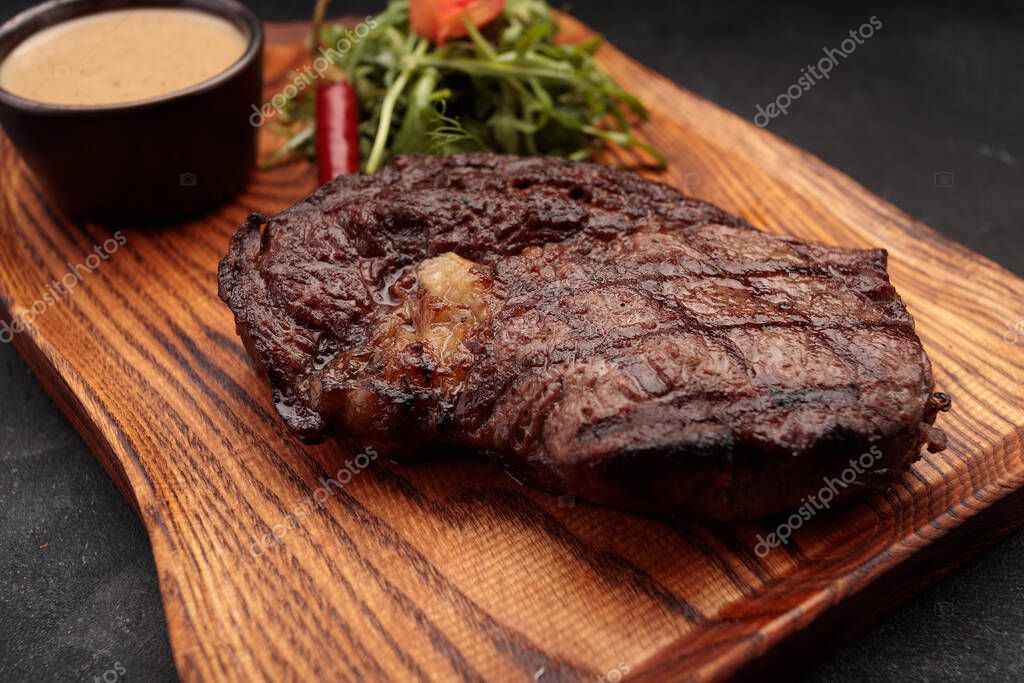 Grilled steak with sauce and herbs, on a wood
