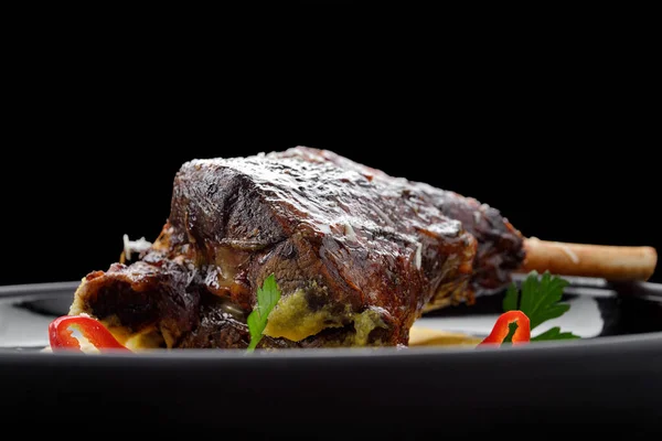 Fried leg of lamb with garnish and pepper, on a dark background — Stock Photo, Image