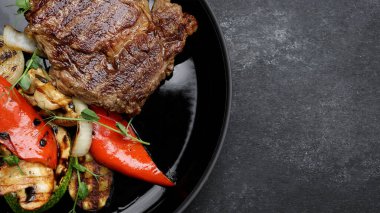 Siyah tabakta ızgara sebzeli biftek. Kabak, soğan, dolma biber.