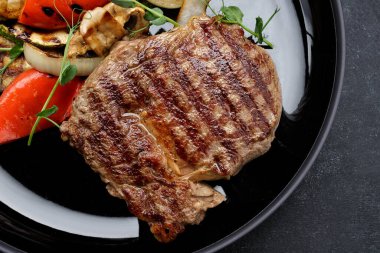 Siyah tabakta ızgara sebzeli biftek. Kabak, soğan, dolma biber.