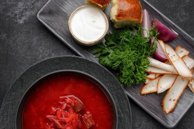 Donutlu Ukrayna çorbası, ekşi krema, domuz yağı ve dereotu, koyu arka planda.