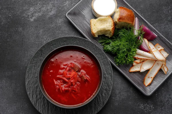 Donutlu Ukrayna çorbası, ekşi krema, domuz yağı ve dereotu, koyu arka planda.